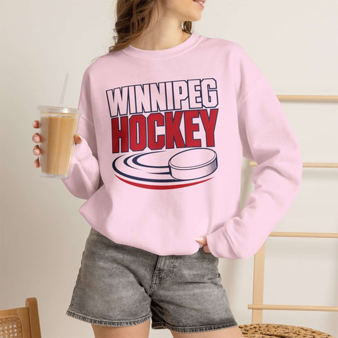 Winnipeg Hockey unisex crewneck sweatshirt featuring vintage navy and red collegiate lettering with a hockey puck graphic, designed by Prairie Life Co.