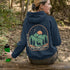 This graphic hoodie features a majestic deer standing against a wilderness backdrop— mountains, towering pines, a glowing moon, and a star-filled night sky.