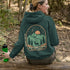This graphic hoodie features a majestic deer standing against a wilderness backdrop— mountains, towering pines, a glowing moon, and a star-filled night sky.