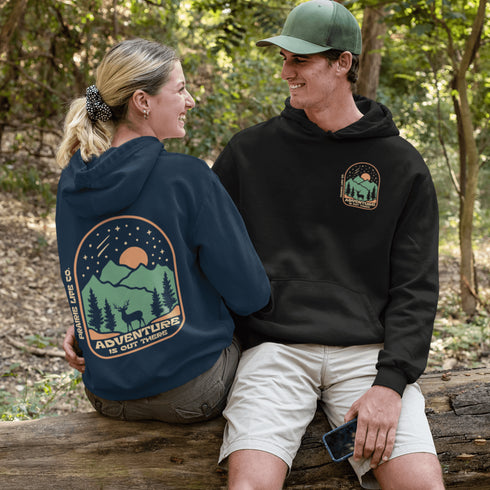 This graphic hoodie features a majestic deer standing against a wilderness backdrop— mountains, towering pines, a glowing moon, and a star-filled night sky.