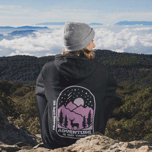 This premium hoodie features a wilderness graphic of a deer under a starry sky, complete with mountains, pine trees, a glowing moon.