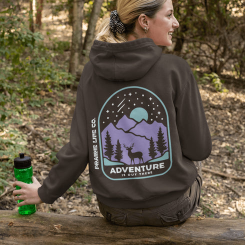 This hoodie features a graphic of a deer standing in the mountains beneath a moonlit sky, everything we love about the quiet magic of the wilderness.