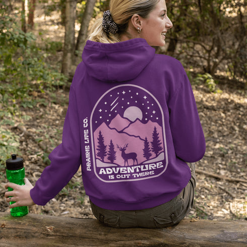 This premium hoodie features a wilderness graphic of a deer under a starry sky, complete with mountains, pine trees, a glowing moon.