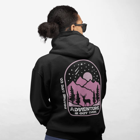 This premium hoodie features a wilderness graphic of a deer under a starry sky, complete with mountains, pine trees, a glowing moon.