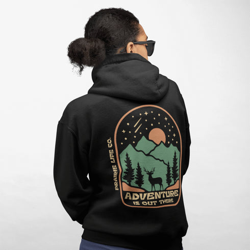This graphic hoodie features a majestic deer standing against a wilderness backdrop— mountains, towering pines, a glowing moon, and a star-filled night sky.