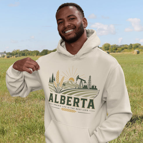 person wearing Alberta prairie life hoodie with farm and landscape design outdoors