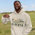 person wearing Alberta prairie life hoodie with farm and landscape design outdoors