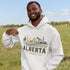 person wearing Alberta prairie life hoodie with farm and landscape design outdoors