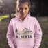 person wearing Alberta prairie life hoodie with farm and landscape design outdoors