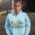 person wearing Alberta prairie life hoodie with farm and landscape design outdoors