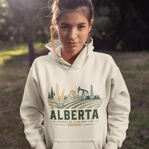 person wearing Alberta prairie life hoodie with farm and landscape design outdoors