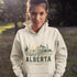 person wearing Alberta prairie life hoodie with farm and landscape design outdoors