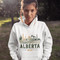 person wearing Alberta prairie life hoodie with farm and landscape design outdoors