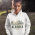 person wearing Alberta prairie life hoodie with farm and landscape design outdoors