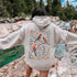 Wrap yourself in the charm of nature with our Among the Leaves Hoodie, a wearable piece of folk art that celebrates the harmony of birds, branches, and blooms.