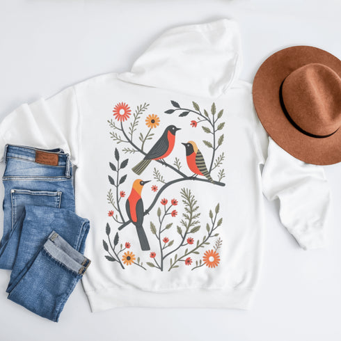 Wrap yourself in the charm of nature with our Among the Leaves Hoodie, a wearable piece of folk art that celebrates the harmony of birds, branches, and blooms.