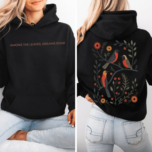 Wrap yourself in the charm of nature with our Among the Leaves Hoodie, a wearable piece of folk art that celebrates the harmony of birds, branches, and blooms.