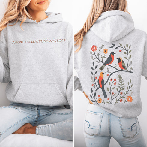 Wrap yourself in the charm of nature with our Among the Leaves Hoodie, a wearable piece of folk art that celebrates the harmony of birds, branches, and blooms.