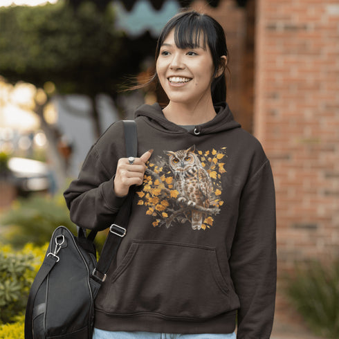 This hoodie features a beautifully detailed owl perched on a branch, surrounded by a scattering of warm-toned autumn leaves.