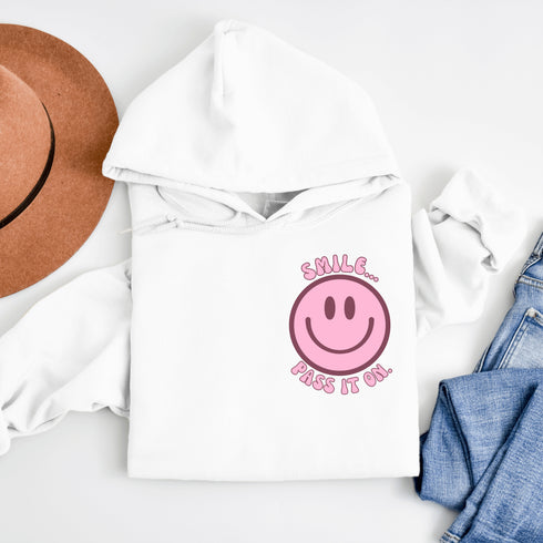 Introducing the latest must-have in your wardrobe that's guaranteed to turn frowns upside down: the Happy Face Hoodie emblazoned with the cheer-spreading command, "Smile...Pass it on." This isn't just any ordinary hoodie; it's your ticket to becoming a walking, talking (and very cozy) ambassador of joy!