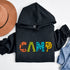 Introducing our vibrant and adventurous camping hoodie! Featuring bold and colorful "Camp" letters adorned with charming camping icons cut out, this shirt is perfect for outdoor enthusiasts and nature lovers alike.
