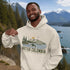 Man wearing a hoodie with a British Columbia design in front of a scenic mountain and lake background