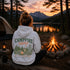 Vintage-inspired outdoor hoodie featuring a matching left chest graphic and large camping-themed back graphic, displayed in a lifestyle mockup inspired by campfires, camping, hiking, and outdoor adventures.