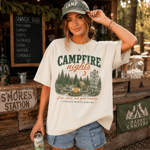 Woman wearing a 'Campfire Nights' t-shirt in a rustic setting with a chalkboard menu.