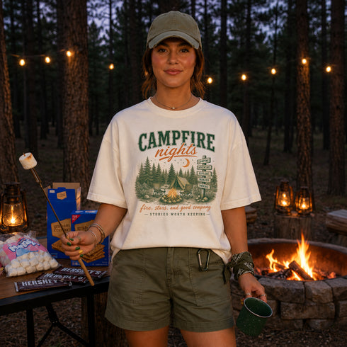 Person wearing a 'Campfire Nights' t-shirt in a forest setting with a campfire and marshmallows.