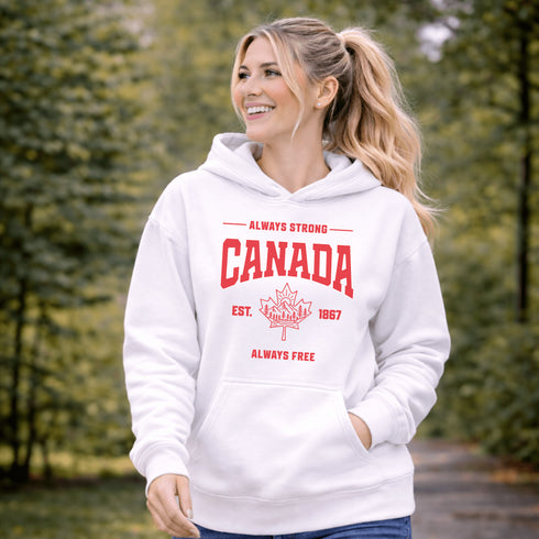 Woman wearing white Canada Always Strong hoodie with red maple leaf graphic and “Est. 1867” design, styled outdoors in a natural setting