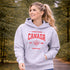 Woman wearing grey Canada Always Strong hoodie with red maple leaf graphic and “Est. 1867” design, styled outdoors in a natural setting
