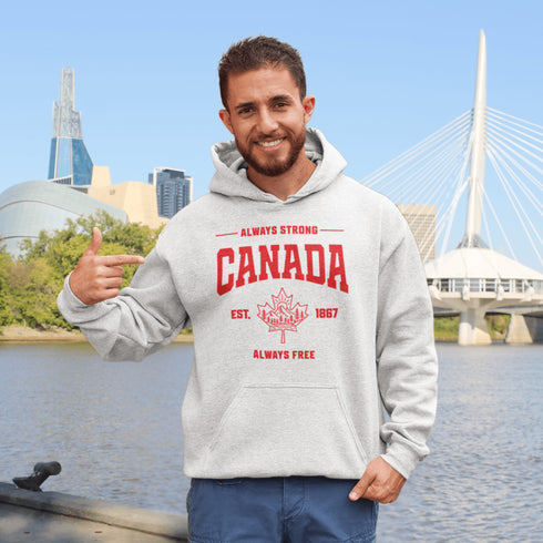 Woman wearing grey Canada Always Strong hoodie with red maple leaf graphic and “Est. 1867” design, styled outdoors in a natural setting