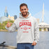 Woman wearing grey Canada Always Strong hoodie with red maple leaf graphic and “Est. 1867” design, styled outdoors in a natural setting