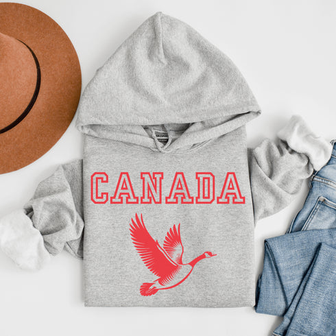 This hoodie celebrates the Canadian goose, wings spread wide, flying across Canada (and probably plotting its next lawn invasion).