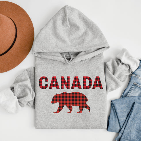 Meet the Plaid & Proud Hoodie, featuring a rugged red & black plaid bear alongside "Canada" in matching plaid lettering—because nothing says “True North strong” like a bear rocking Canadian flannel.