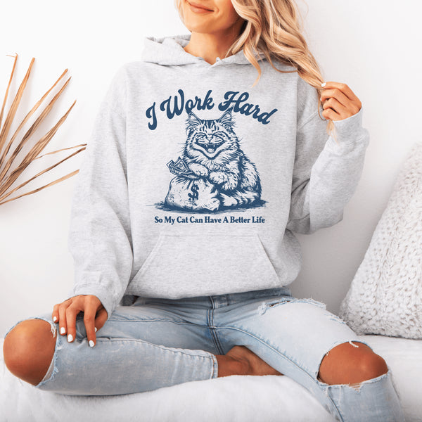This hoodie captures the purr-fect truth with a cheeky design featuring a laughing cat clutching a bag of cash, living its best life.