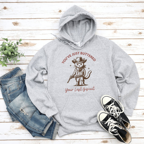 This hoodie is purr-fect for anyone who loves cats, chaos, and a healthy dose of cowboy attitude. Featuring a grumpy cat in a cowboy hat, pointing a tiny pistol