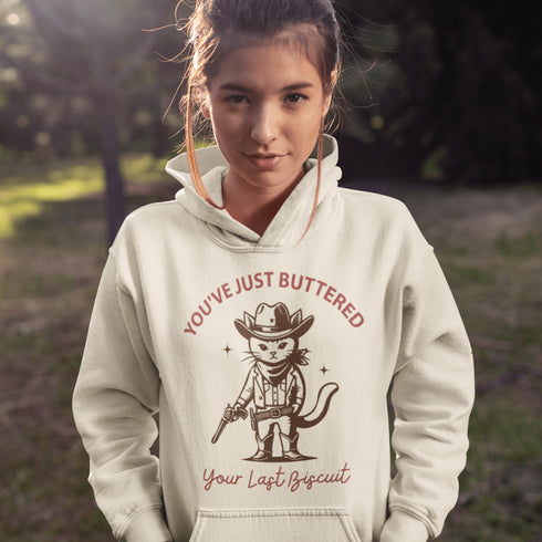 This hoodie is purr-fect for anyone who loves cats, chaos, and a healthy dose of cowboy attitude. Featuring a grumpy cat in a cowboy hat, pointing a tiny pistol