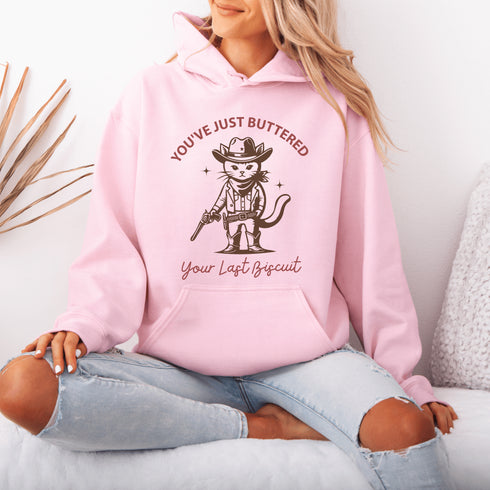 This hoodie is purr-fect for anyone who loves cats, chaos, and a healthy dose of cowboy attitude. Featuring a grumpy cat in a cowboy hat, pointing a tiny pistol