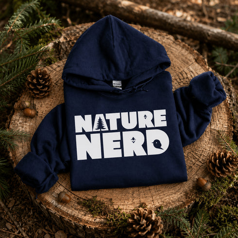 Navy hoodie with 'Nature Nerd' text on a wooden stump with pine cones and branches.