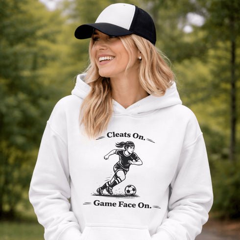 Woman wearing a Cleats On Game Face On soccer hoodie with player graphic, holding coffee outdoors