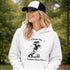Woman wearing a Cleats On Game Face On soccer hoodie with player graphic, holding coffee outdoors