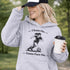 Woman wearing a Cleats On Game Face On soccer hoodie with player graphic, holding coffee outdoors