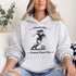Woman wearing a Cleats On Game Face On soccer hoodie with player graphic, holding coffee outdoors