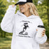 Woman wearing a Cleats On Game Face On soccer hoodie with player graphic, holding coffee outdoors