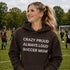 Woman wearing a hoodie with 'Crazy proud always loud soccer mom' text on a soccer field.