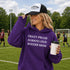 Woman wearing hoodie with "Crazy Proud Always Loud Soccer Mom" text standing on a soccer field during a youth soccer game