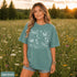Comfort Colors garment-dyed t-shirt featuring a vintage botanical design with dragonflies, butterflies, bees, wildflowers, dandelions, floating seeds, hearts, stars, and a crescent moon.