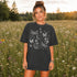 Comfort Colors garment-dyed t-shirt featuring a vintage botanical design with dragonflies, butterflies, bees, wildflowers, dandelions, floating seeds, hearts, stars, and a crescent moon.