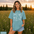 Comfort Colors garment-dyed t-shirt featuring a vintage botanical design with dragonflies, butterflies, bees, wildflowers, dandelions, floating seeds, hearts, stars, and a crescent moon.